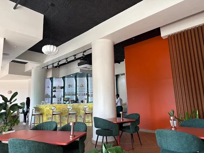 La salle : fauteuils en velours vert, tables terracotta et bar en onyx doré