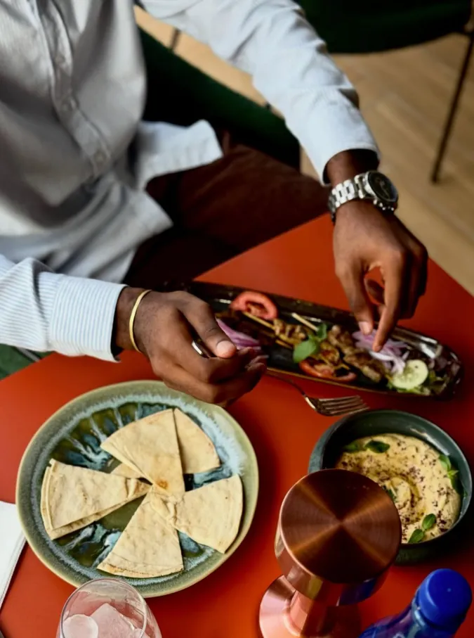 Houmous, pain pita et brochettes sur une table terracotta
